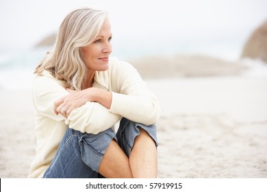 Senior Woman On Holiday Sitting On Winter Beach