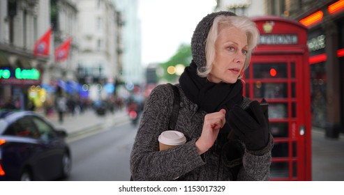 Senior Woman On Vacation In London Waiting For Rideshare With Cell Phone