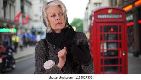 Senior Woman On Vacation In London Waiting For Rideshare With Cell Phone