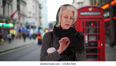 Senior Woman On Vacation In London Waiting For Rideshare With Cell Phone