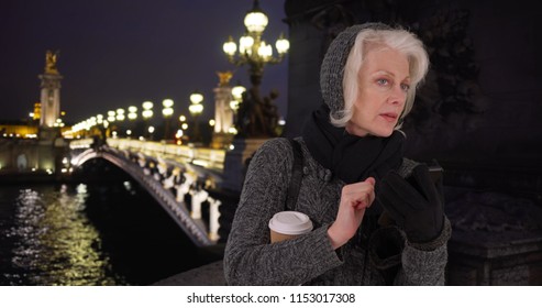 Senior Woman On Vacation In Paris Waiting For Rideshare Smartphone