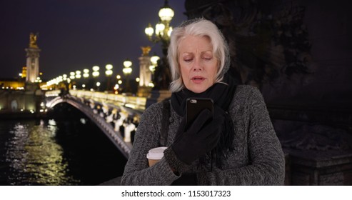 Senior Woman On Vacation In Paris Waiting For Rideshare Smartphone