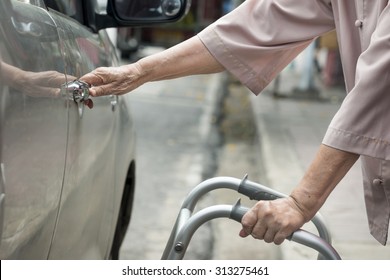 Senior Woman Open Car Door With Walker On Street.