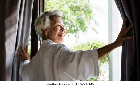 Senior woman opening the curtains - Powered by Shutterstock