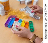 A senior woman organizing the pills she must take during the week and putting them in colored pillboxes.