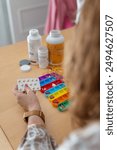 A senior woman organizing the pills she must take during the week and putting them in colored pillboxes.