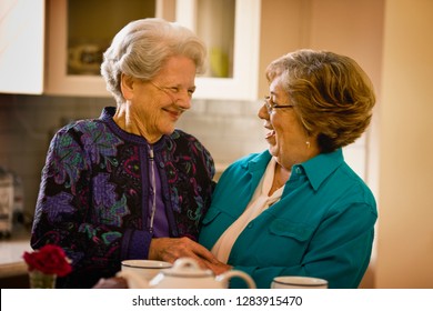 Senior Woman With An Oxygen Nose Hose (cannula) And A Mature Women Smile And Hug Over Cups Of Tea.