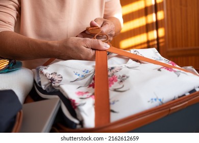 Senior Woman Packing Her Stuff Into A Suitcase On The Bed Preparing For Summer Vacation Trip. Traveling Preparation Concept