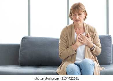 senior woman pain suffering from heart disease on sofa - Shutterstock ID 2134422561