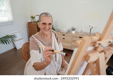 Senior Woman Painting on Canvas in Bright Modern Home Studio with Natural Light - Powered by Shutterstock