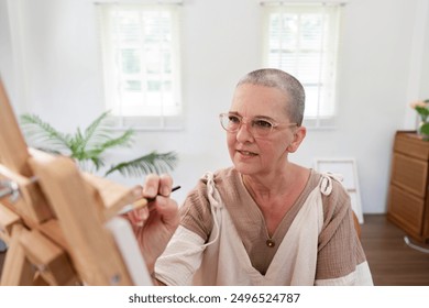 Senior Woman Painting on Canvas in Bright Modern Home Studio with Natural Light - Powered by Shutterstock