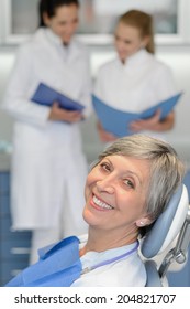 Senior Woman Patient With Dentist Team At Dental Surgery Smiling