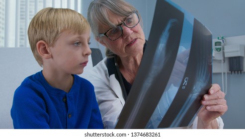 Senior woman pediatrician showing x-ray of hand to little boy patient. Child at doctors office - Powered by Shutterstock