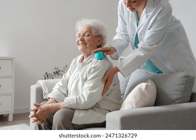 Senior woman and physical therapist massaging her shoulder with ball at home - Powered by Shutterstock