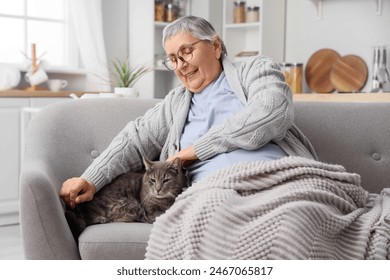 Senior woman with plaid and cat resting on sofa at home - Powered by Shutterstock