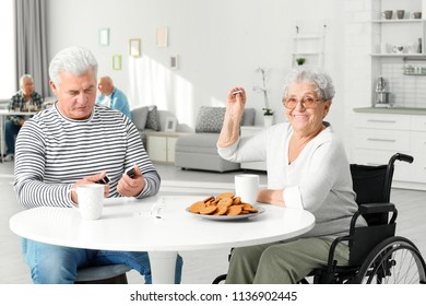 Senior Woman Playing Dominoes With Her Friend While Having Breakfast At Care Home