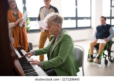 Senior Woman Playing At Piano In Choir Rehearsal.