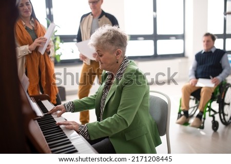 Senior woman playing at piano in choir rehearsal.