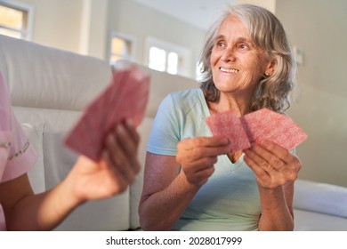 Senior Woman Plays Cards With Friends On Game Night At Home Or In The Retirement Home