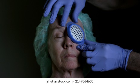 A senior woman post cataract removal surgery getting a protective eye shield placed over the operated eye.