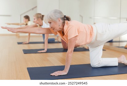 Senior woman practicing yoga during group training in studio. - Powered by Shutterstock