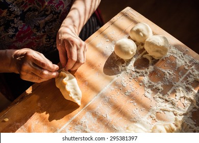 Senior woman prepares pies on a table in her home kitchen