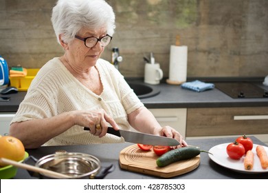 Senior woman preparing healthy food from fresh vegetables in kitchen. - Powered by Shutterstock