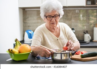 Senior Woman Preparing A Meal With Vegetables In The Kitchen.