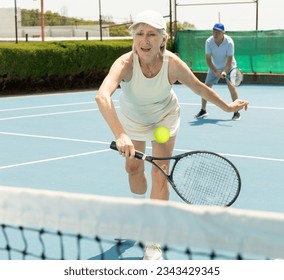 Senior woman preparing to return serve during game of tennis. Dedicated tennis player. - Powered by Shutterstock