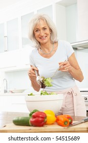 Senior Woman Preparing Salad In Modern Kitchen