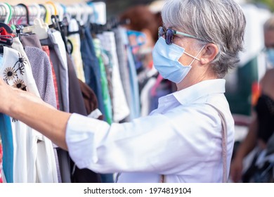 Senior Woman With Protective Face Mask At Flea Market Choosing Clothes