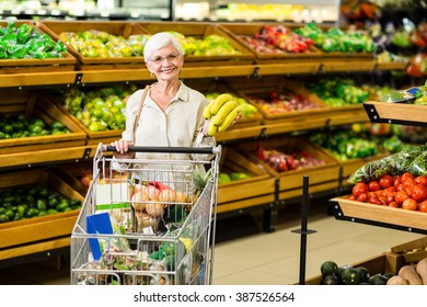 Senior Woman Putting Banana In Her Trolley In Supermarket