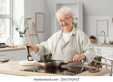 Senior woman putting fried cottage cheese pancakes on plate in kitchen - Powered by Shutterstock