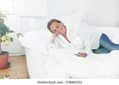 Senior Woman Reading In Bed A Tablet