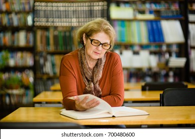 Senior woman reading book in library - Powered by Shutterstock