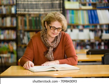 Senior Woman Reading Book In Library