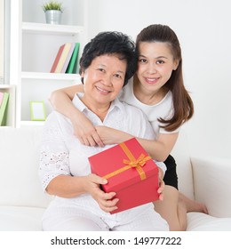 Senior Woman Receiving A Gift From Adult Daughter, Beautiful Asian Family At Home.