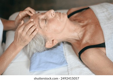 Senior woman receiving a relaxing massage from a therapist on a massage table - Powered by Shutterstock