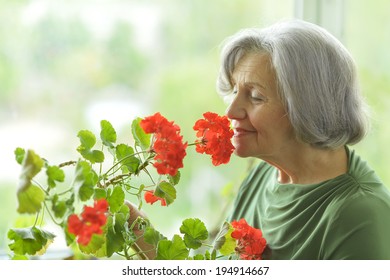 Senior Woman With Red Flowers At Home