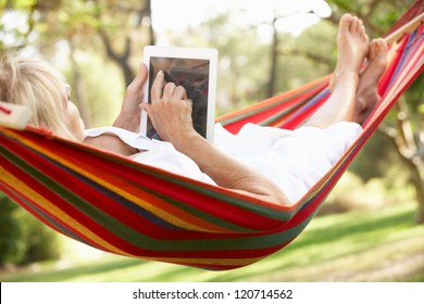 Senior Woman Relaxing In Hammock With  E-Book - Powered by Shutterstock