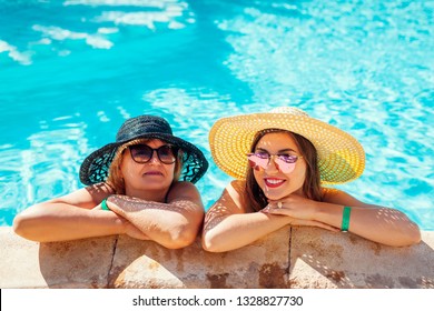 Senior woman relaxing with her adult daughter in hotel swimming pool. People enjoying summer vacation. Mother's day - Powered by Shutterstock