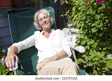 Senior Woman Relaxing On Lounge Chair In Garden