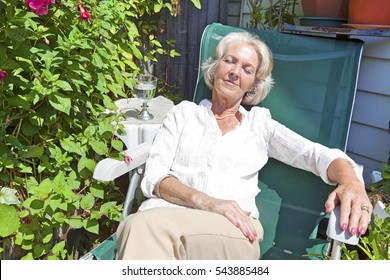 Senior Woman Relaxing On Lounge Chair In Garden