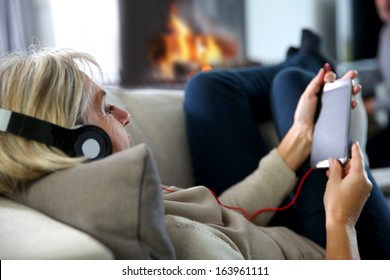 Senior Woman Relaxing In Sofa With Music Headset On