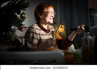 Senior Woman With Remote Control In Hand Watching TV On New Year Night