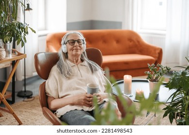 Senior woman resting with cup of tea in her living room, listening music. - Powered by Shutterstock