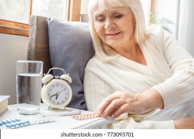 Senior woman resting at home in bed taking pills elderly lifestyle - Powered by Shutterstock