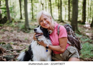 Senior woman resting and stroking her dog during walking in forest. - Powered by Shutterstock