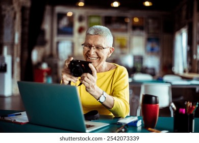 Senior woman reviewing photos on camera in office setting - Powered by Shutterstock