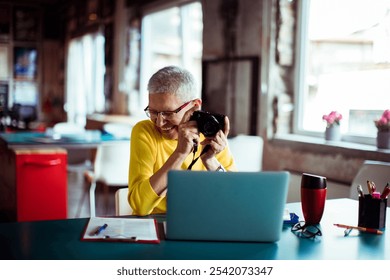 Senior woman reviewing photos on camera in office setting - Powered by Shutterstock